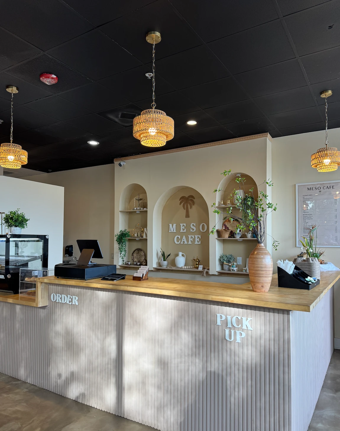 Inside Meso Cafe: arched niches with a woven palm and the Meso Cafe sign behind the wooden counter